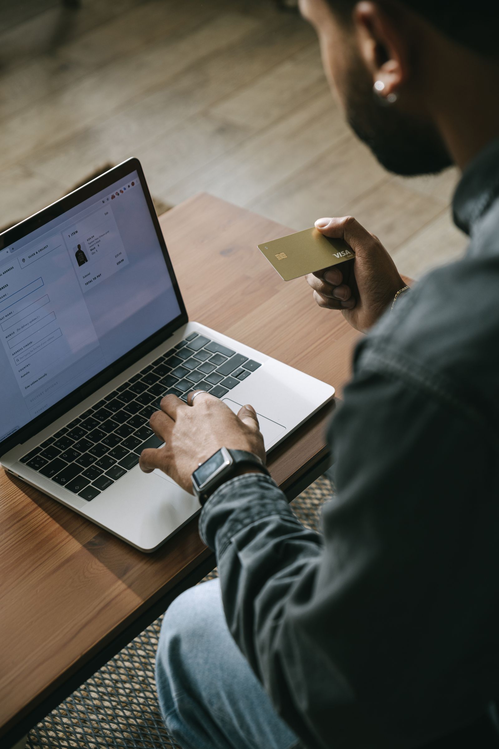 A person holding a card while using a laptop